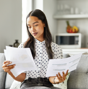 Woman holding many papers and looking closely at them