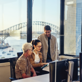 Three professionals looking over notes in an office overlooking Sydney harbour.