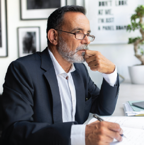 Mature aged male professional taking notes and thinking