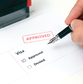 Person holding pen over a checkbox saying visa approved